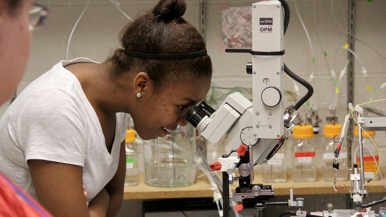 An REU student looking through a microscope